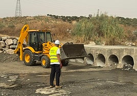 Una máquina retroexcavadora y el alcalde de Cártama, Jorge Gallardo en la zona de desatoro en los conductos del paso del arroyo Torre con el arroyo Gorrino.