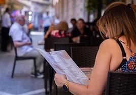 Una mujer mira la carta de un restaurante en el centro de Málaga.