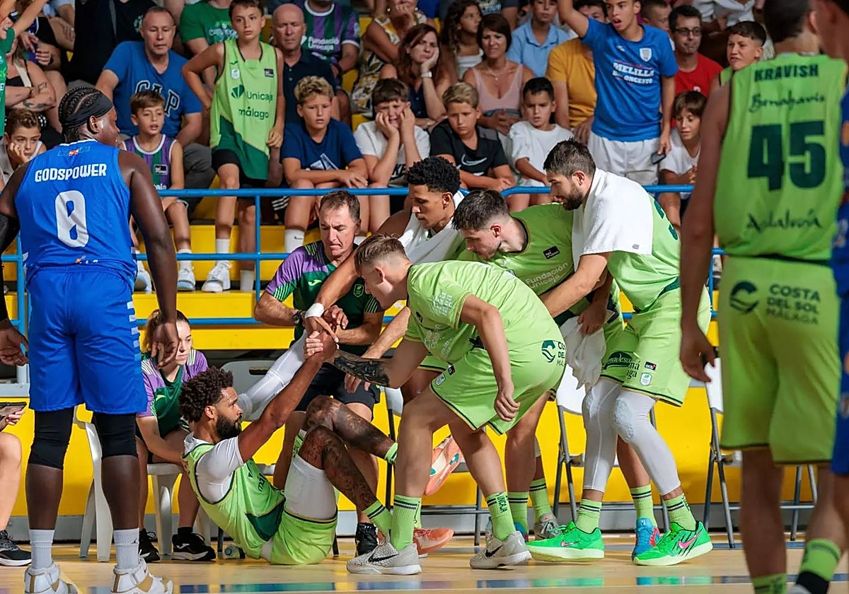 Jugadores del Unicaja ayudan a Webb a levantarse tras un lance del juego.