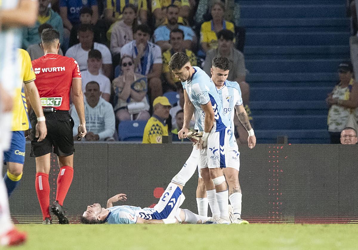 Montero ayuda a Puga a estirar su pierna derecha, con Murillo detrás.