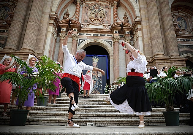 Dos devotos bailando por malagueñas ante la fachada principal de la Catedral.