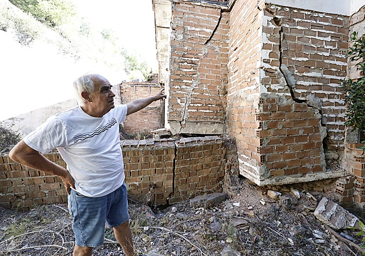 Antonio Méndez muestra las grietas de la zona trasera de una de las casas que están deshabitadas.