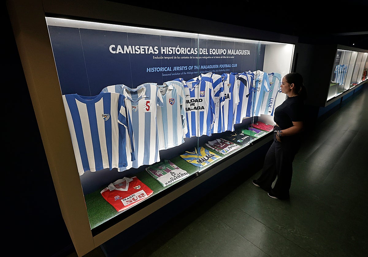 Una guía del museo observa la vitrina de camisetas históricas.