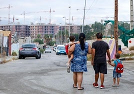 Una familia del barrio el martes pasado antes de comenzar el colegio con las grúas y las nuevas construcciones de fondo.