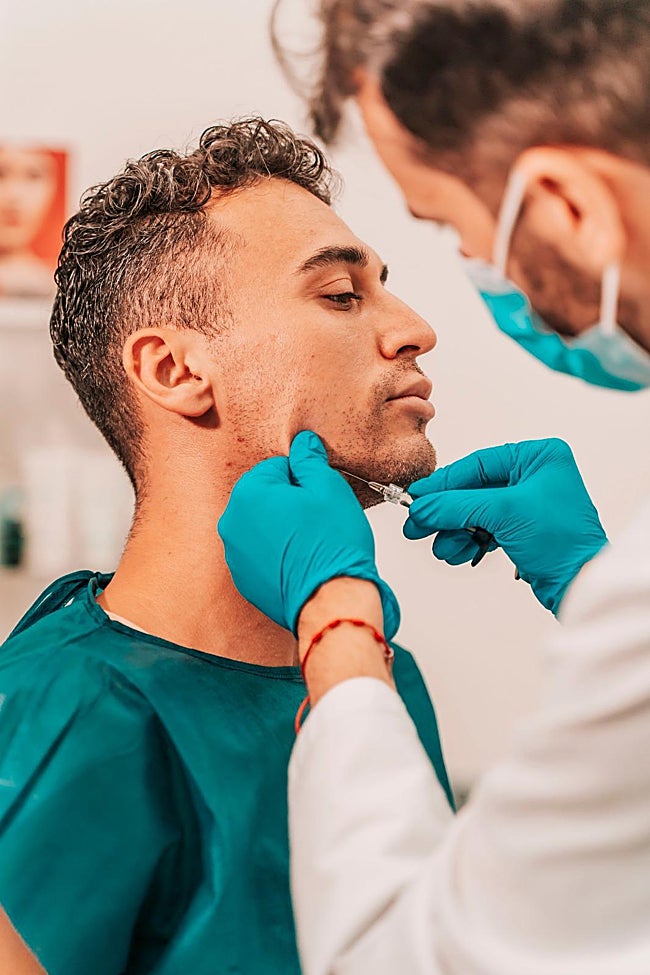 El doctor Andrés Bernete inyecta ácido hialurónico a un paciente.