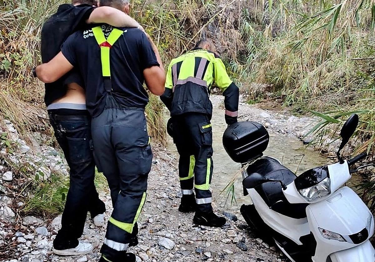 Los efectivos del Consorcio Provincial de Bomberos, en el rescate del joven, junto a la motocicleta.