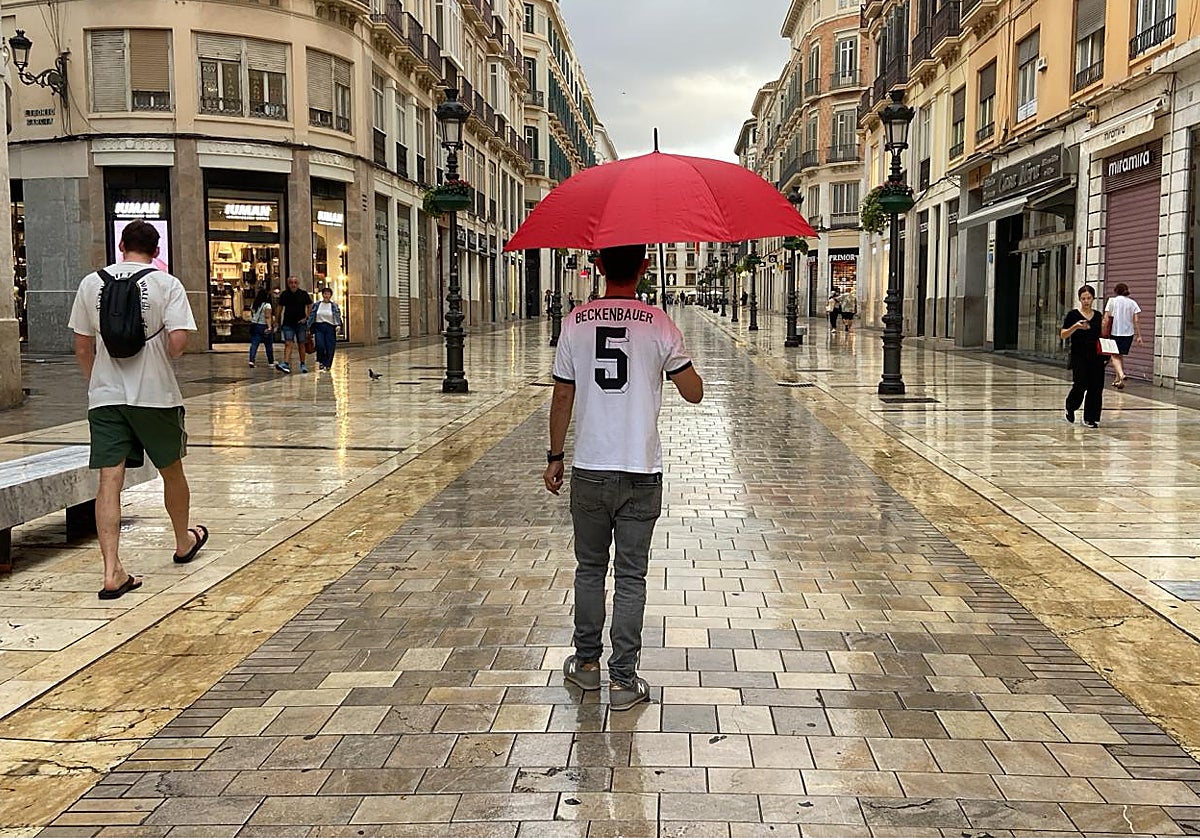 Mangas cortas y paraguas hoy en una atípica estampa de otoño en la calle Larios.