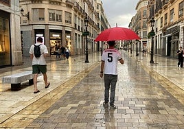 Mangas cortas y paraguas hoy en una atípica estampa de otoño en la calle Larios.