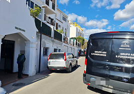 Imagen del día de los hechos, con el furgón funerario y un agente custodindo la entrada a la urbanización en la que tuvo lugar el crimen.