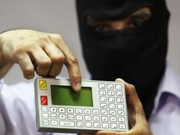 Un oficial de policía enmascarado muestra un dispositivo que sirve para descifrar mensajes codificados. / Archivo