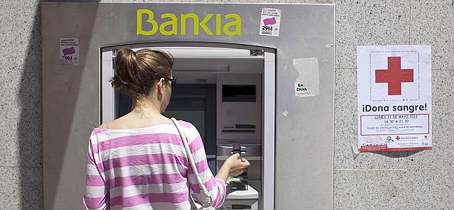 Una joven saca dinero de un cajero de Bankia. / Archivo