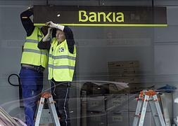 Dos trabajadores colocan un cartel de Bankia. / R. Pelaez (Reuters)