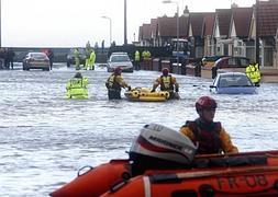 Miembros de los equipos de emergencias utilizan zodiacs para moverse por las calles de Rhyl en Gales. / Efe