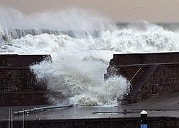 Dos personas caminan ante la brecha originada en el rompeolas del puerto de Bermeo. / Foto: Alfredo Aldai (Efe) | Vídeo: Atlas