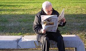 Un jubilado lee el periódico en un banco. / Archivo
