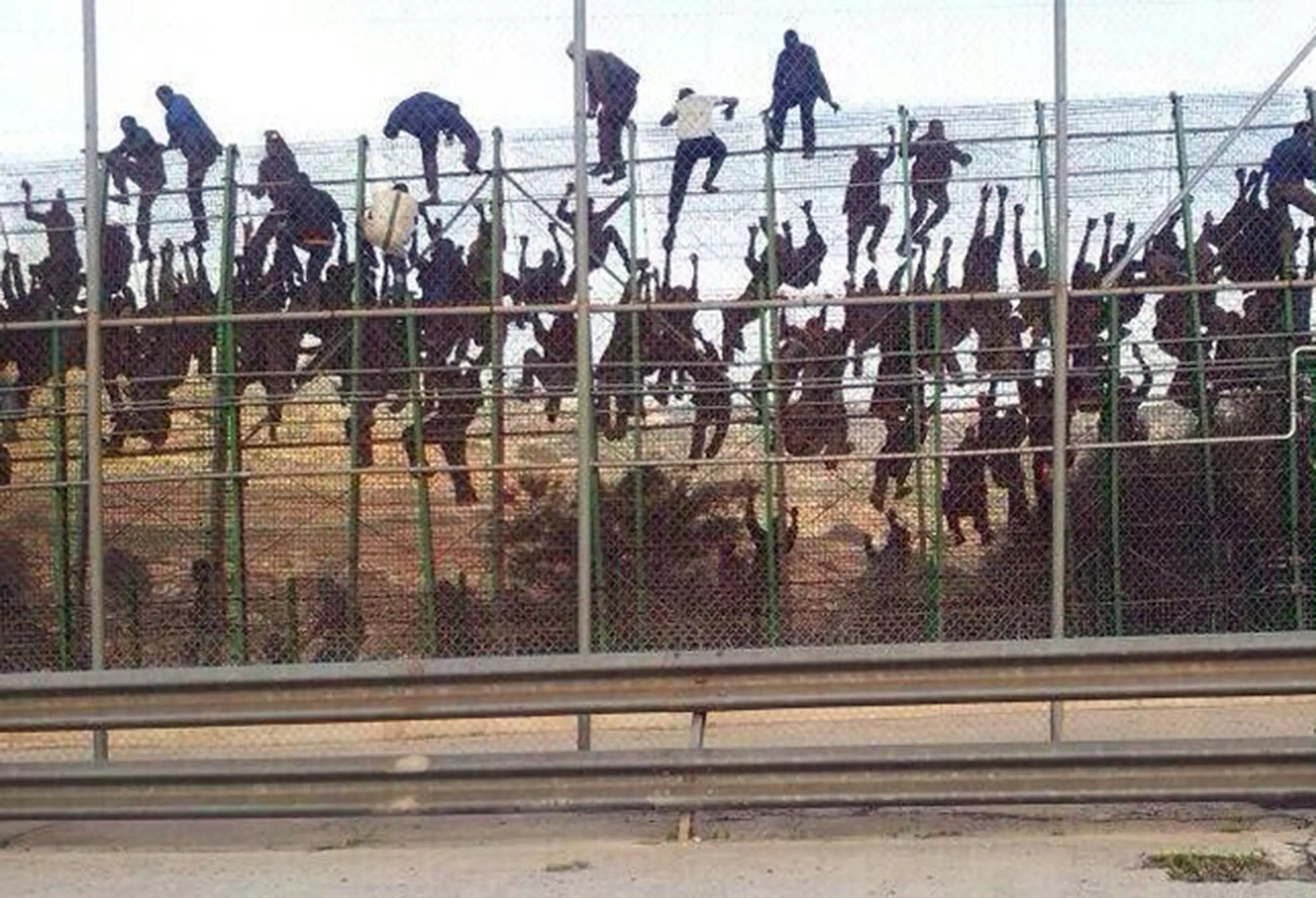 Numerosos inmigrantes, en pleno salto a la valla de Melilla. / Foto distribuida por la agencia Colpisa | Vídeo: Atlas