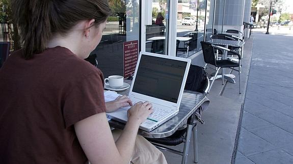 Una mujer utiliza su portátil en una cafetería.