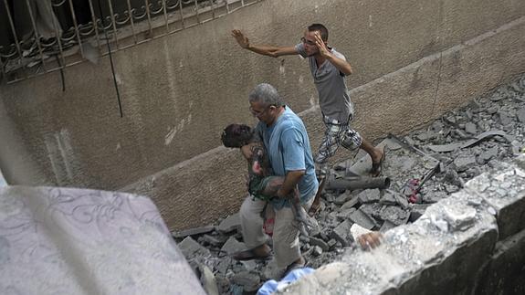 Un hombre traslada a un niño herido durante un bombardeo en la Franja. 