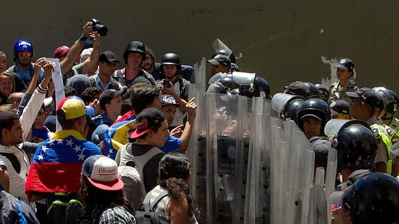 Un grupo de personas protesta frente a miembros de la Policía Nacional Bolivariana (PNB).