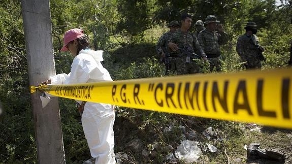 Un policía forense mexicano coloca la cinta policial. 
