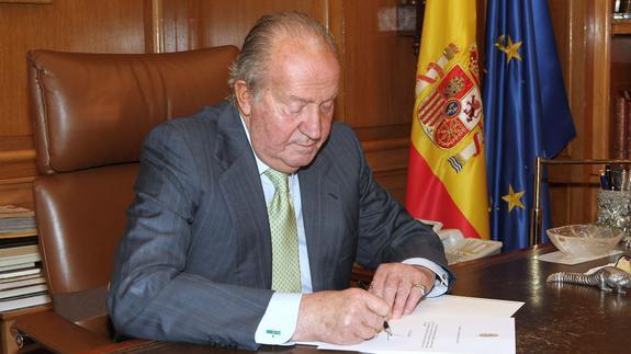 El rey Juan Carlos I firma el documento de su abdicación. 