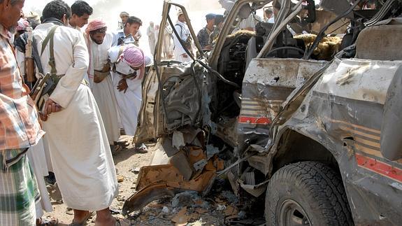 Vigilantes armados y yemeníes inspeccionan los restos del atentado.