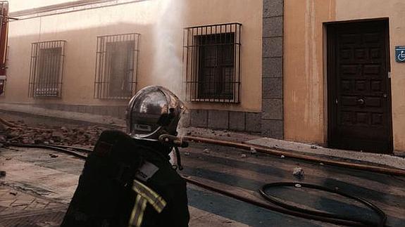 Los bomberos tratán de extinguir el incendio en los edificios colindantes.