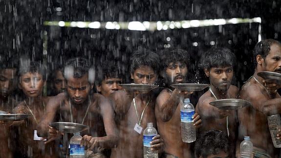 Varios inmigrantes recogen agua en el campo de refugiados de Kayin Chaung, en Birmania.