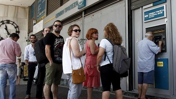 Varios atenienses ante un cajero automático.