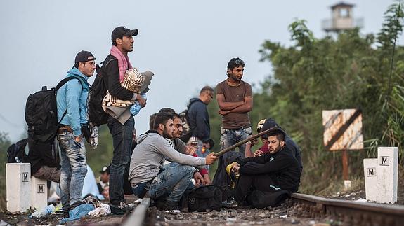 Un grupo de inmigrantes descansa en la vía de tren en la frontera entre Hungría y Serbia.