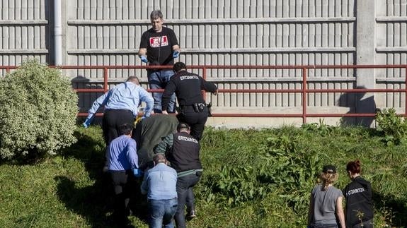 Personal de la funeraria y agentes de la Ertzaintza trasladan el cuerpo de la mujer fallecida.