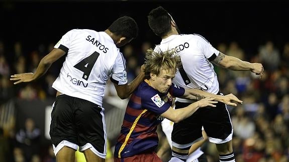 Rakitic (c) entre dos jugadores del Valencia. 