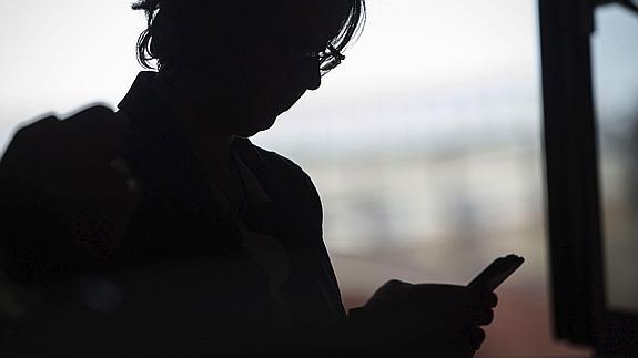 Una mujer consulta su teléfono móvil.