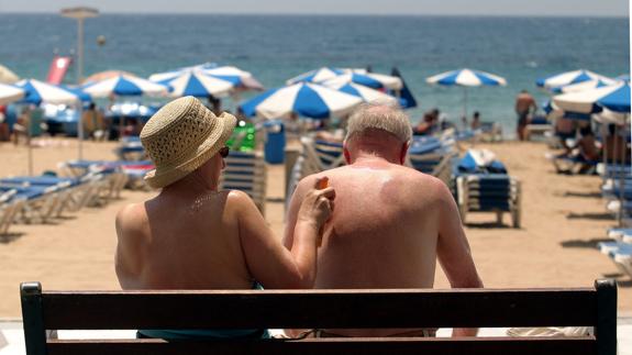 Pareja de turistas aplicándose crema solar en Benidorm.