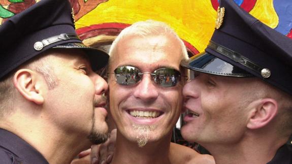Dos gais vestidos de policías besan a un compañero durante el desfile del 'Christopher Street Day' en Berlín. 