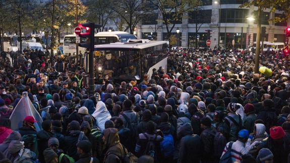 Centenares de inmigrantes esperan para subir a un autobús durante el desalojo de un campamento en el distrito 19 de París.