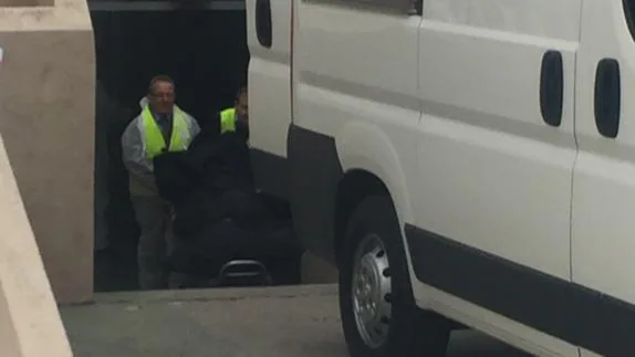 Trabajadores de los servicios funerarios trasladan el cadáver del hombre fallecido.