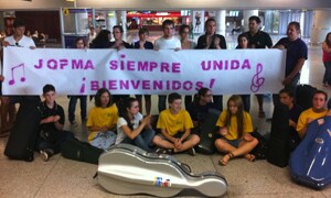 Los músicos, en el aeropuerto de Málaga con la pancarta de bienvenida que les aguardaba. :: Vídeo y foto: Álvaro Cabrera