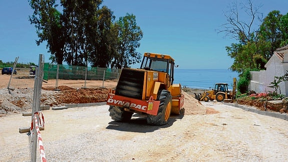 Máquinas ejecutan los trabajos de asfaltado del nuevo acceso peatonal a la playa de El Pinillo desde la A-7.