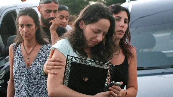 La hija de María Antonia sujeta una foto de su madre a su llegada al cementerio. 