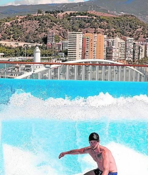 Un turista hace surf en el barco, con Málaga de fondo.