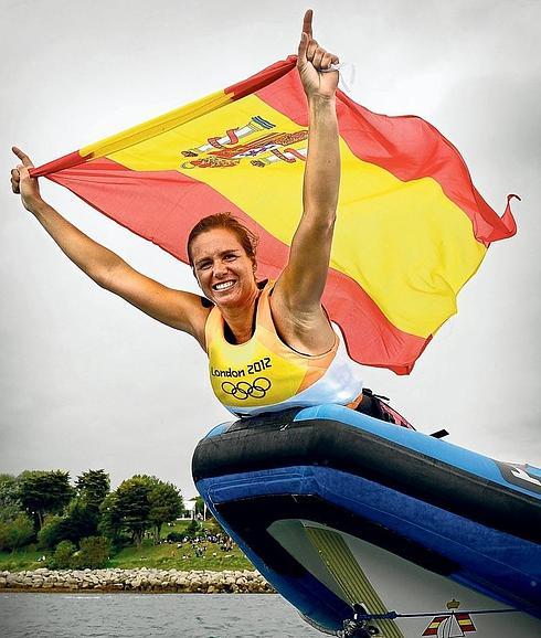 Marina Alabau ondea la bandera española sobre la proa de una gomona tras conquistar el oro en RS-X (wind surf) en los Juegos Olímpicos de Londres. 
