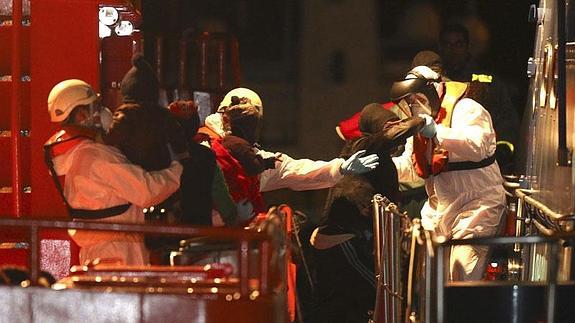Miembros de la Guardia Civil desembarcan a dos de los bebes, junto a otros inmigrantes que iban en la embarcación. 