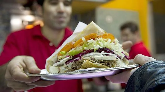 Un camarero sirve un kebab en pan de pita.