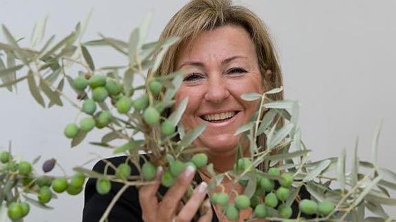 Paz Hurtado, presidenta ejecutiva de Hutesa Agroalimentaria, sostiene una vara de olivo cuajada de aceitunas.