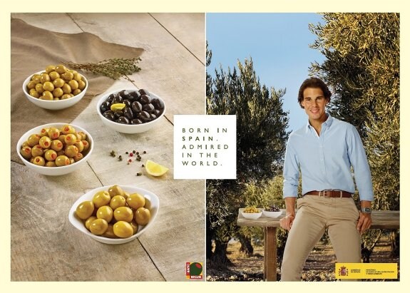 Un sonriente Nadal posa para la campaña entre olivares y junto a un par de platitos de aceitunas de mesa.