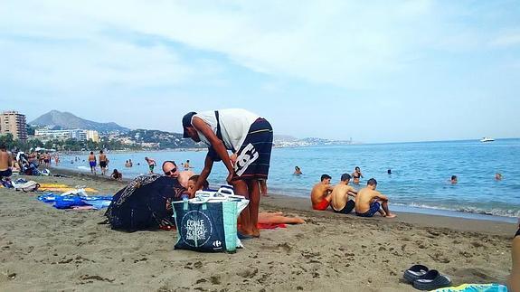 Un hombre recorre la playa ofreciendo sus productos a los bañistas.