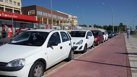 El carril bici pasa junto al acceso de muchos edificios y va pegado a los vehículos estacionados.