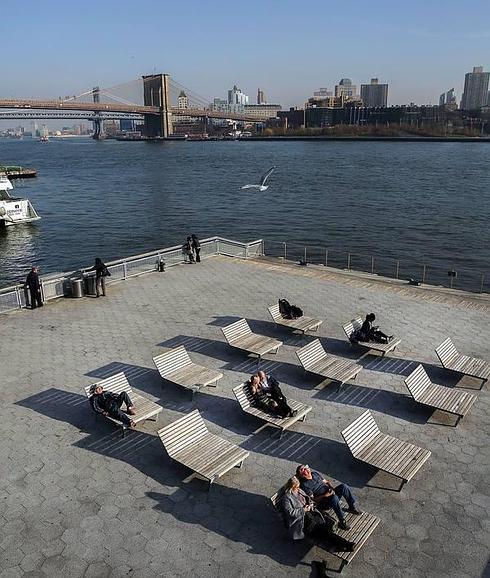 Neoyorquinos disfrutando del sol de diciembre en un antiguo muelle del bajo Manhattan.