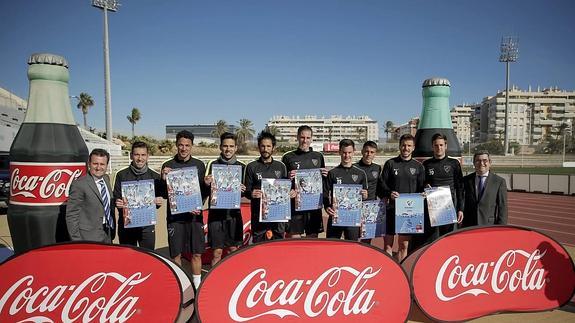 Jugadores del Málaga posan con el cartel junto a representantes de Coca-Cola